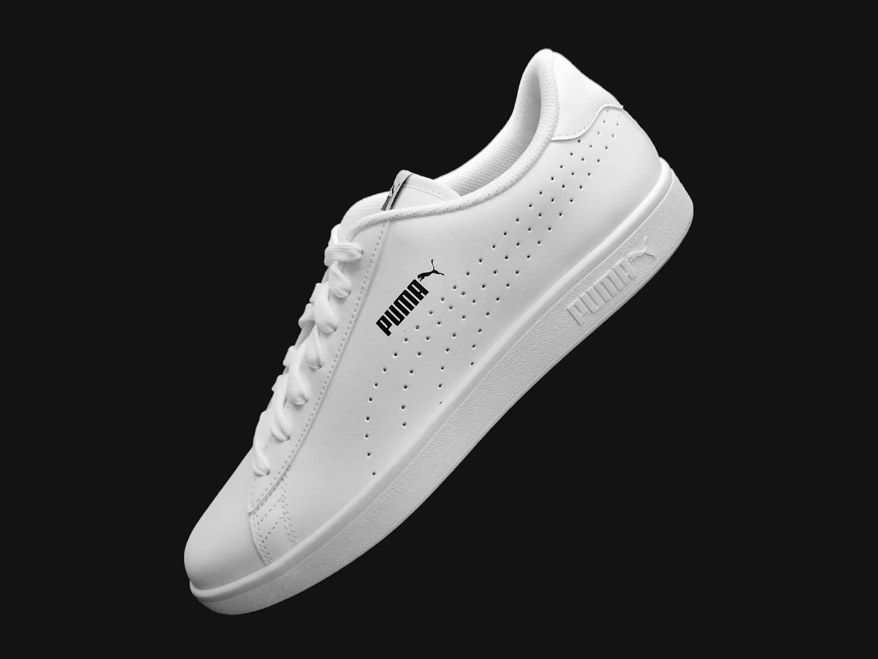White leather sneaker floating on a black background